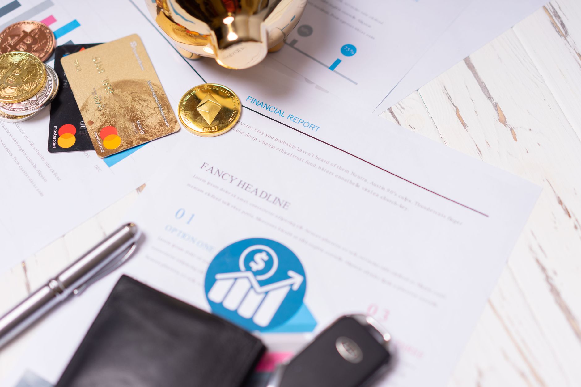Close-up of financial documents, credit cards, coins, and a pen on a wooden desk.