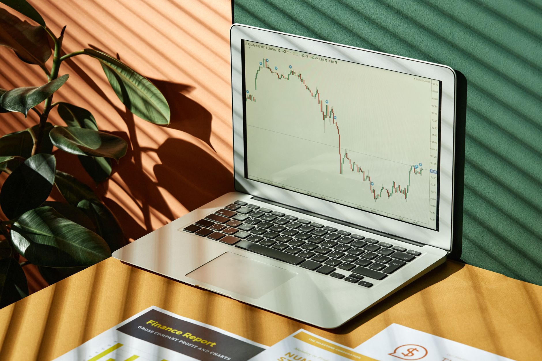 Laptop displaying a financial graph with reports, in a sunlit workspace.