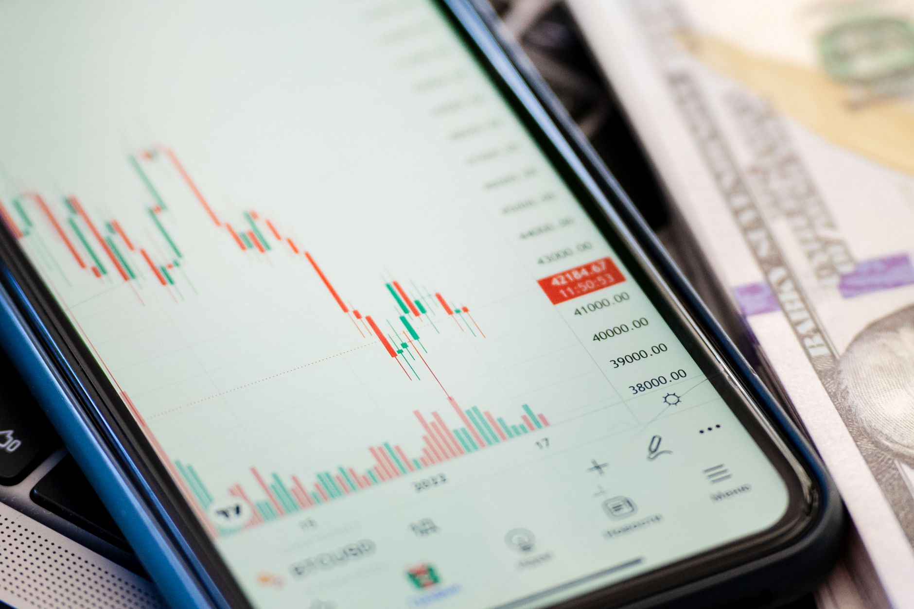Detailed view of stock market data on a smartphone with US dollars in the background, illustrating trading.