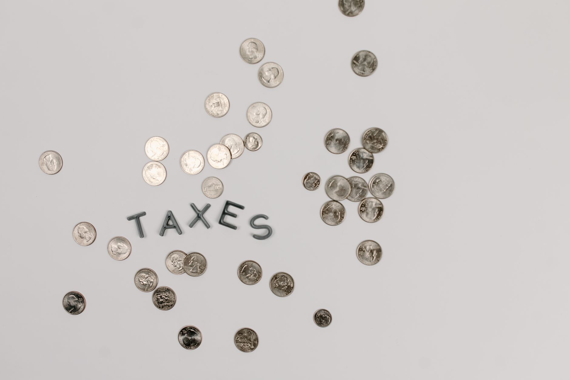 A visually striking flatlay of coins with 'Taxes' text on a white surface, ideal for financial concepts.