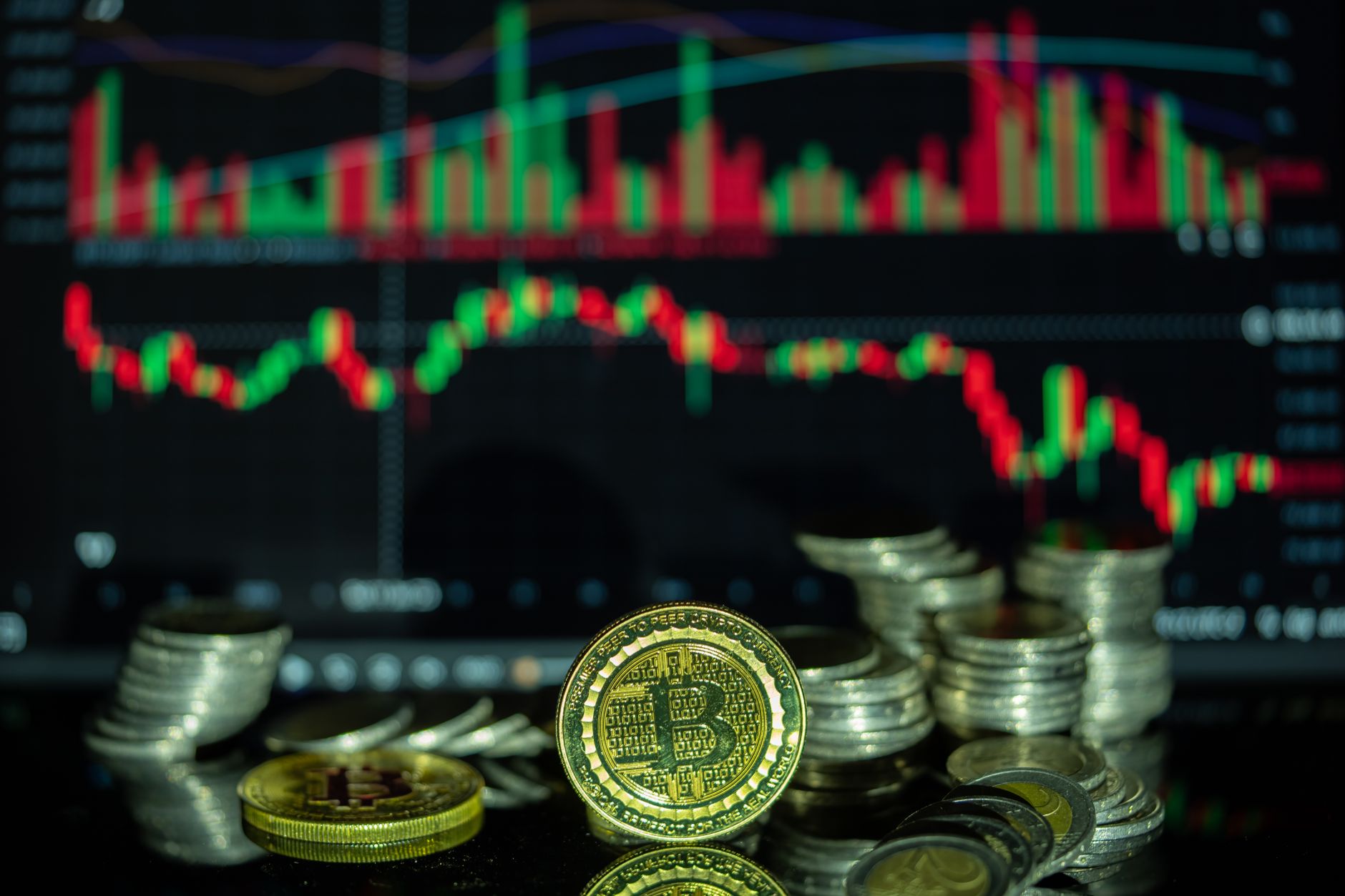 Golden Bitcoin and stacked coins in front of a colorful financial chart, symbolizing cryptocurrency market dynamics.