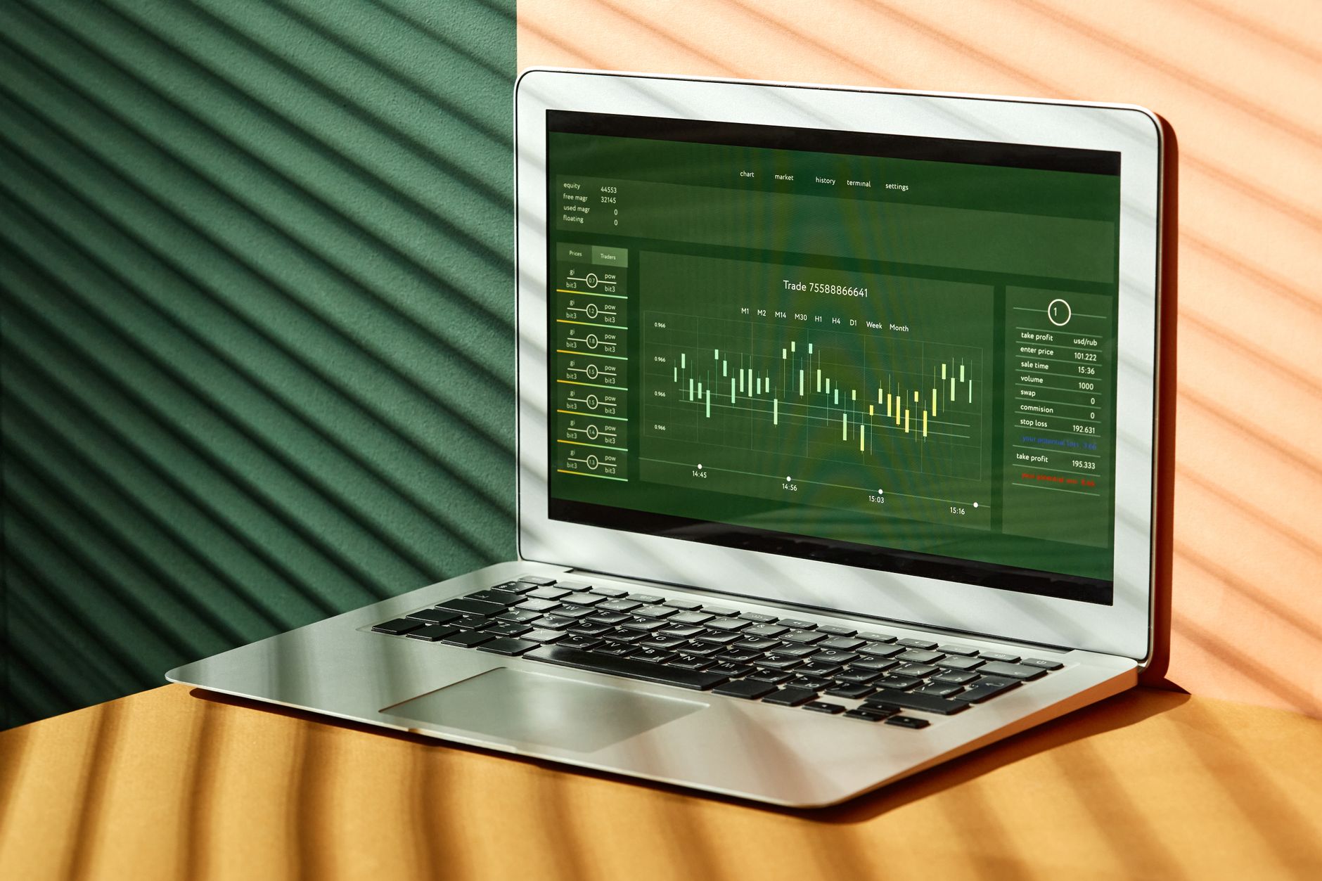 A laptop displaying stock market data with shadows from window blinds casting dramatic patterns.
